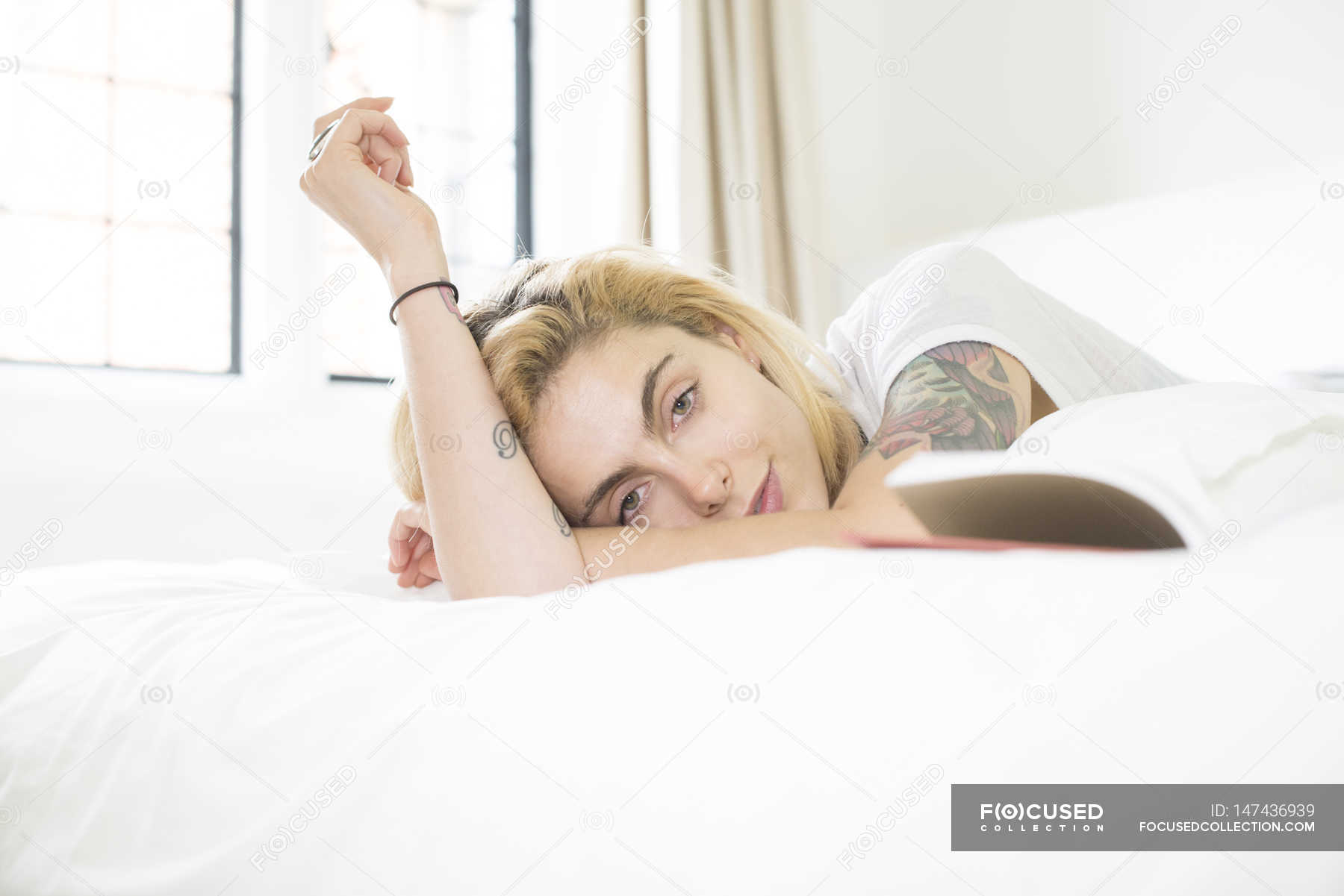 Woman With Tattoos Lying On Bed With Book Female Cool Stock Photo