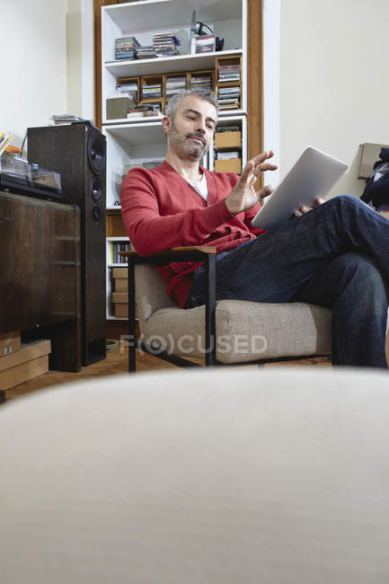 Mature Man Sitting On Chair With Digital Tablet Smiling Technical