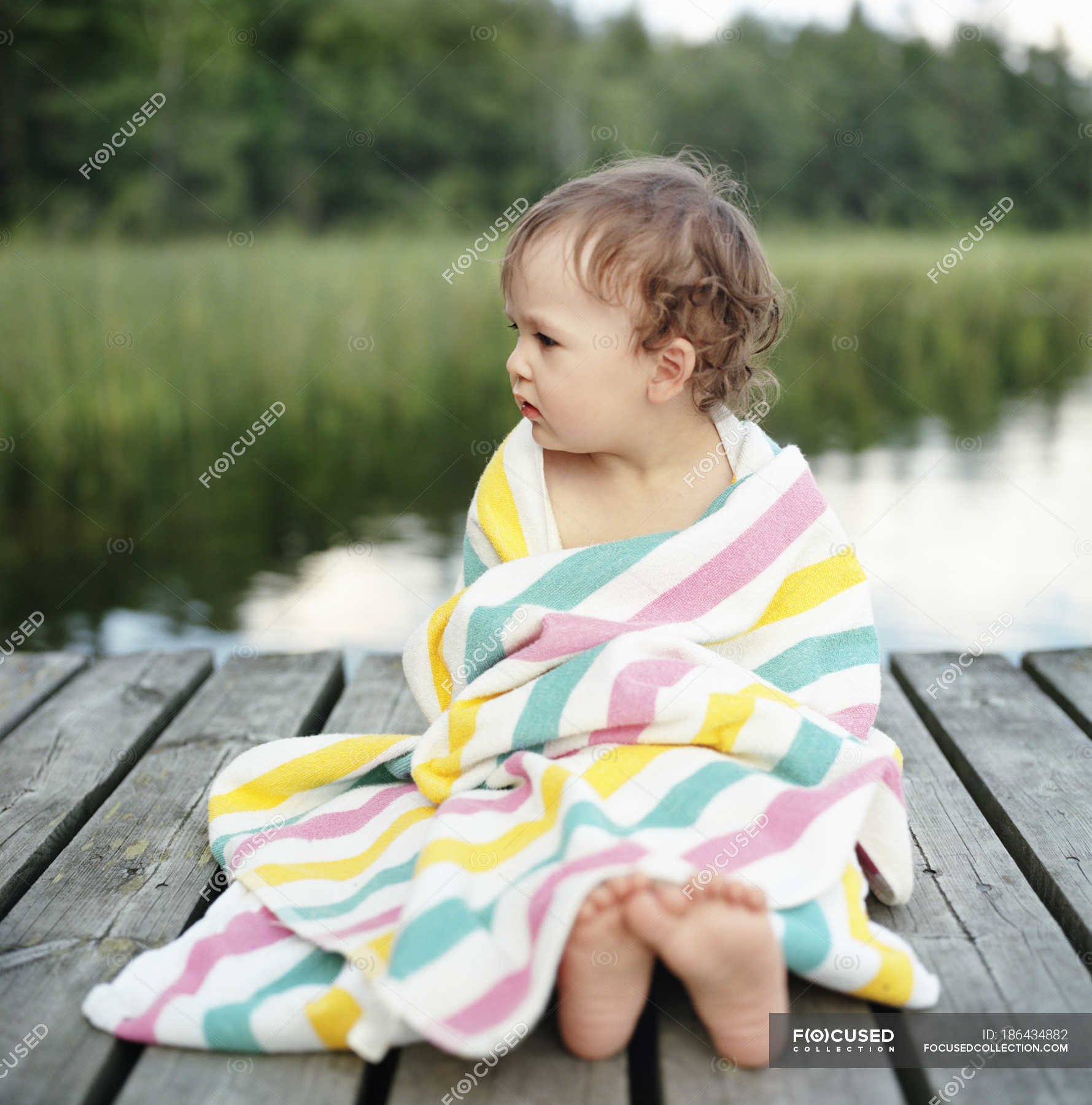 Portrait Of Girl Wrapped In Towel Sitting On Jetty Differential Focus People Lake Stock