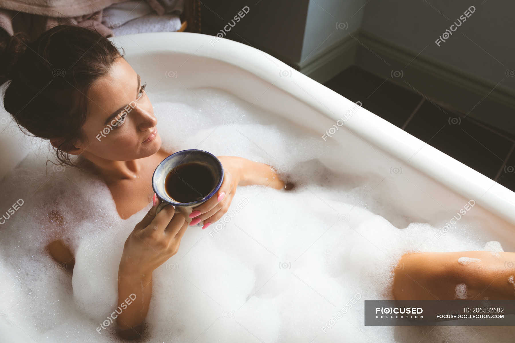 Молодая женщина купается в ванне с пеной