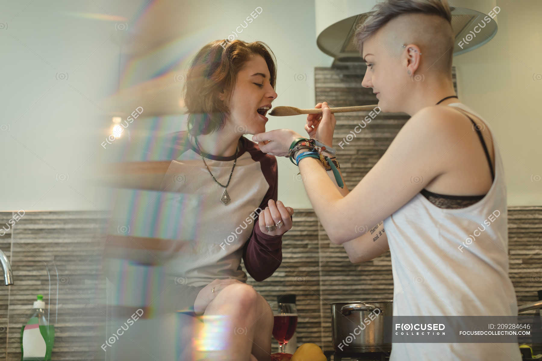Lesbian Couple Food Tasting In Kitchen At Home Caucasian Ethnicity