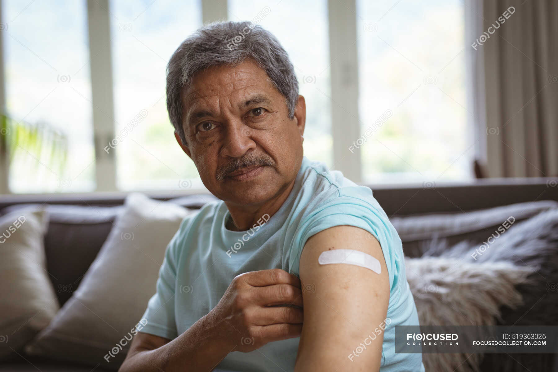 Portrait Of Biracial Senior Man Showing Bandage On Arm After Covid