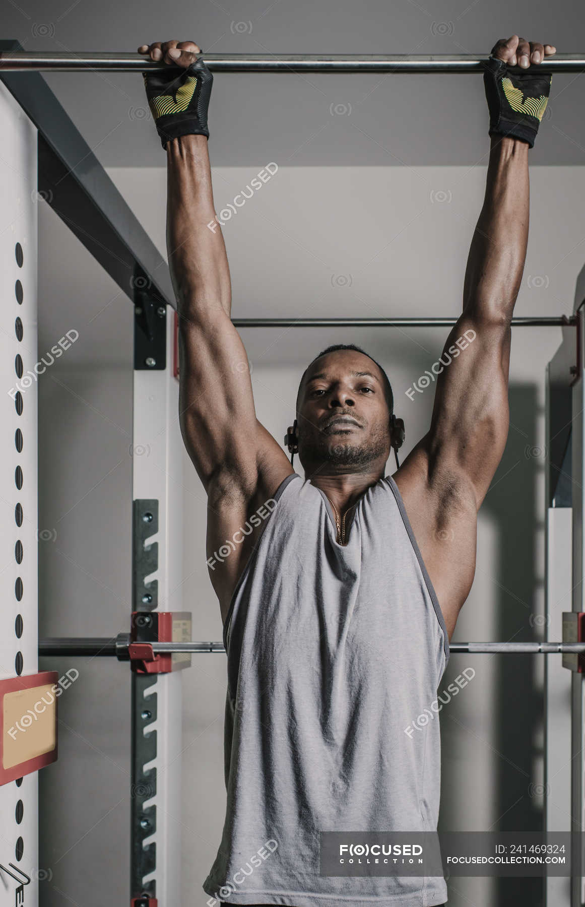 Black Muscular Guy Hanging On Bar In Gym People Looking At Camera Stock Photo