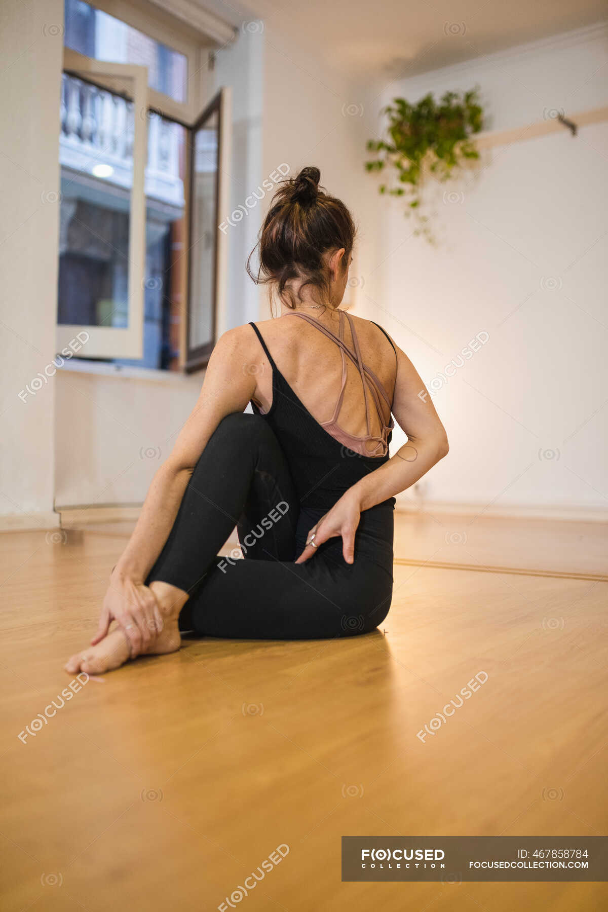 Back View Of Anonymous Barefoot Female In Sports Clothes Stretching Leg