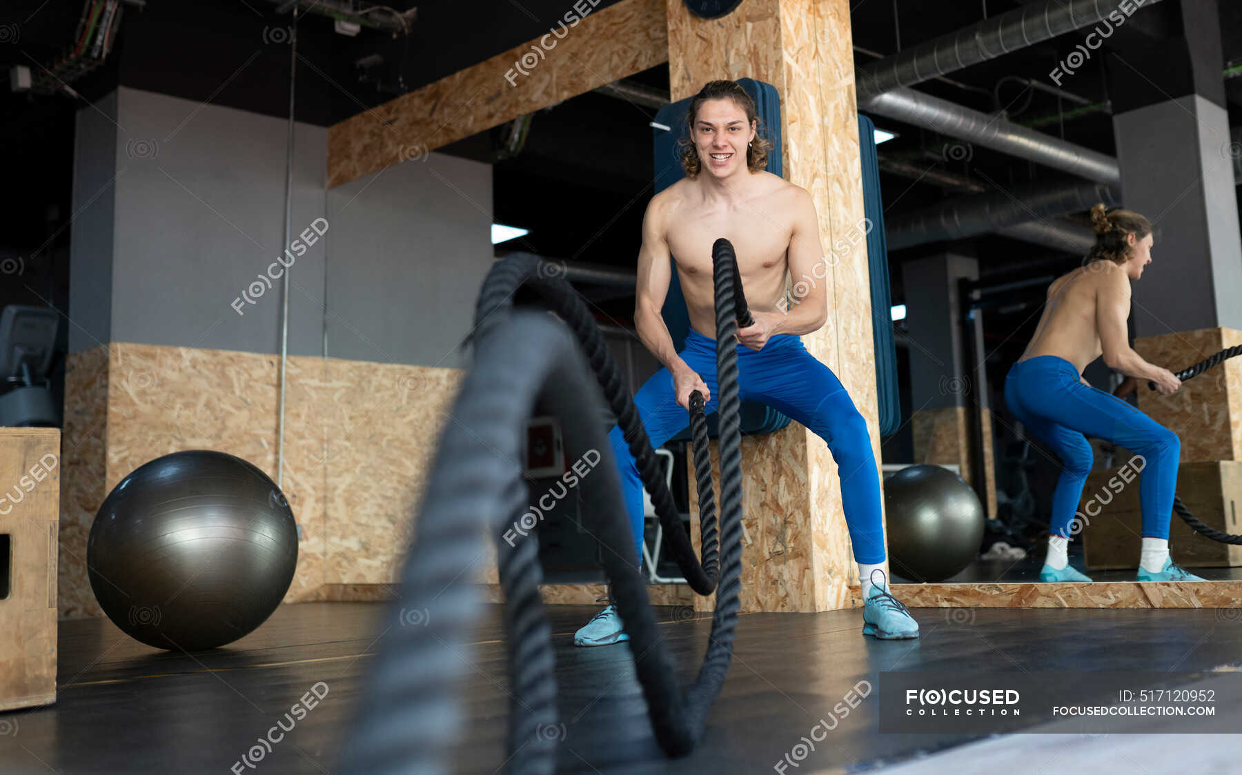 Muscular Male Athlete With Naked Torso Exercising With Battle Rope