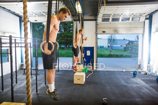 Gli atleti che esercitano sugli anelli ginnici al Healthclub — Foto stock