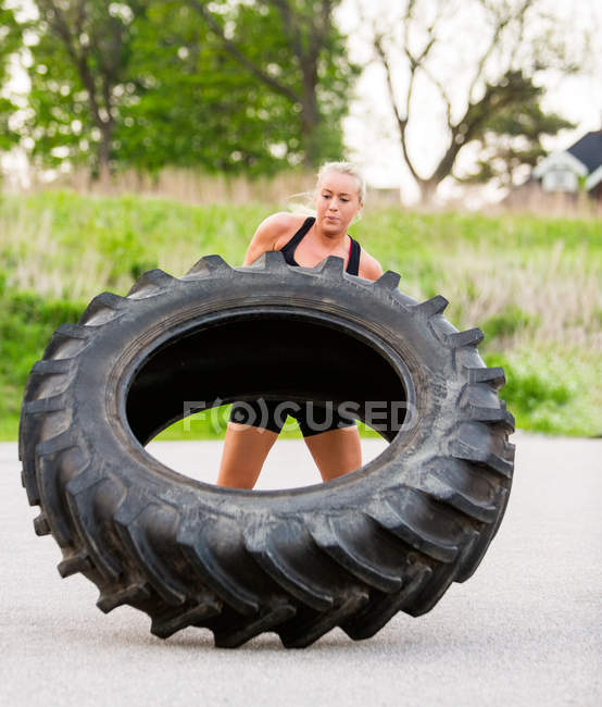 Frau kippt Reifen im Freien um — Stockfoto