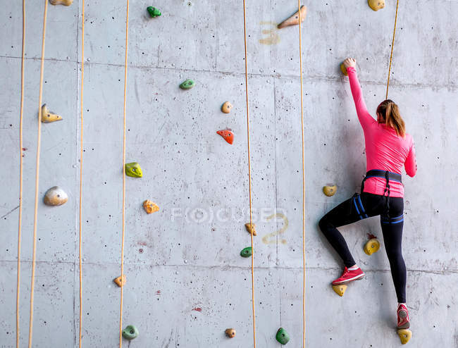 Красива молода жінка починає сходження на велику штучну стіну — стокове фото