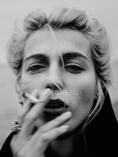 Жінка палить сигарету і дивиться на камеру — стокове фото