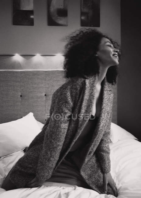 Girl sitting on bed and laughing — Stock Photo