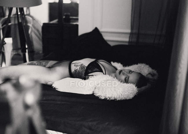 Tätowierte Frau liegt auf Bett — Stockfoto