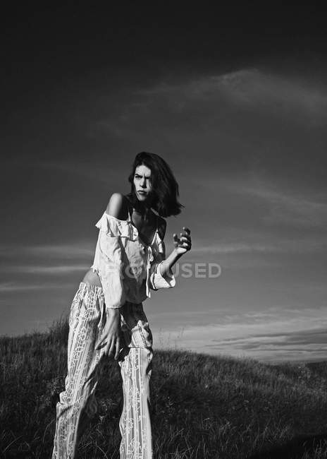 Frau posiert auf Wiese mit ländlicher Landschaft — Stockfoto