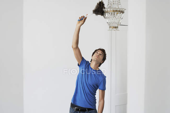 Man dusting crystal chandelier — Stock Photo