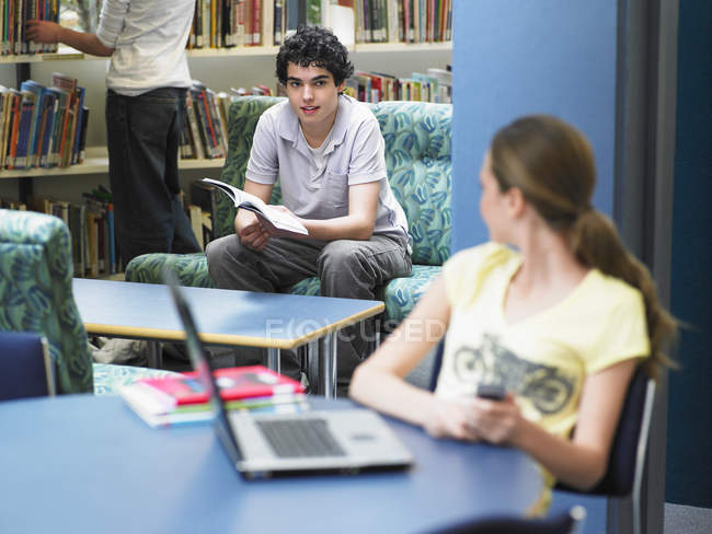 Menina olhando para menino na biblioteca — Fotografia de Stock