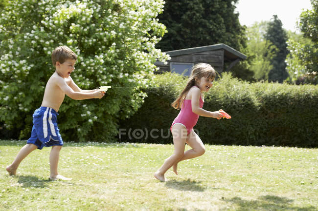 Ragazzo tiro ragazza con pistola ad acqua — Foto stock