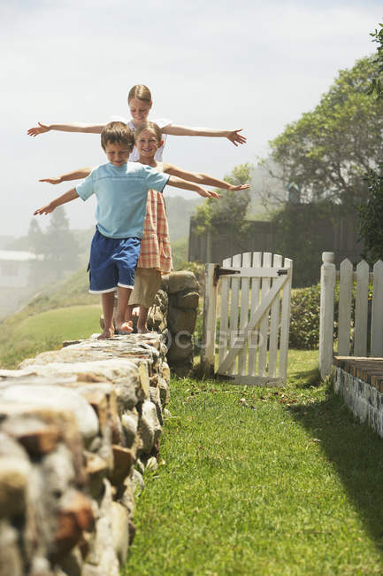 Enfants marchant sur un mur de pierre — Photo de stock