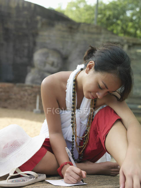 Mujer escribiendo sobre durmiendo estatua de Buda - foto de stock