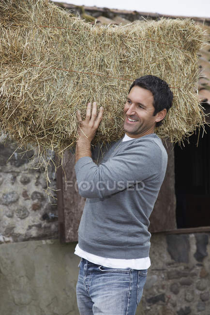 Agricoltore sorridente con fieno — Foto stock