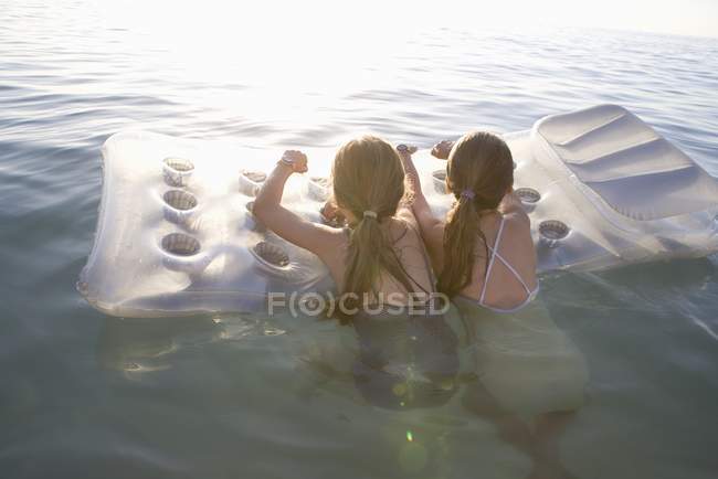 Twin sisters on inflatable mattress — Stock Photo