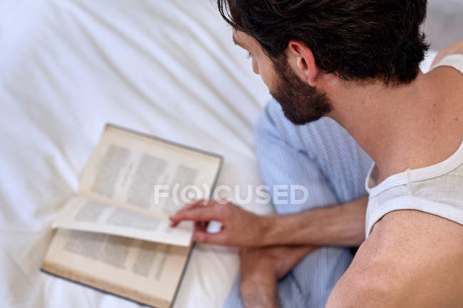 Людина на ліжку читає книгу — стокове фото