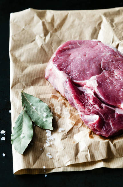 Bifteck de côtelette cru sur papier brun avec sel — Photo de stock