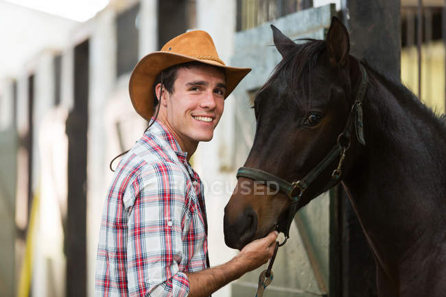 Ковбой з конем в стайні — стокове фото
