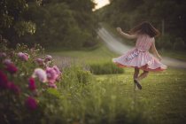 Девушка в платье танцует на зеленой лужайке — стоковое фото