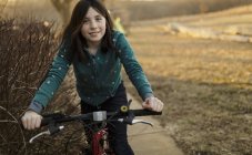 Sonriente chica morena montar en bicicleta - foto de stock