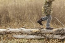 Boy running on dry logs — Stock Photo