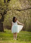 Girl standing under blooming tree branches — Stock Photo