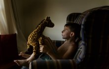 Мальчик играет с игрушкой жирафа — стоковое фото