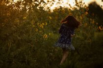 Брюнетка бежит в цветущих подсолнухах — стоковое фото