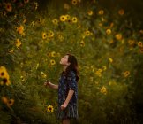 Brünettes Mädchen steht in der Nähe blühender Sonnenblumen — Stockfoto
