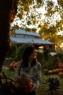 Chica sosteniendo la calabaza en el jardín de otoño - foto de stock
