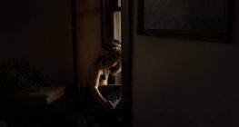 Задумливий хлопчик сидить біля вікна — стокове фото