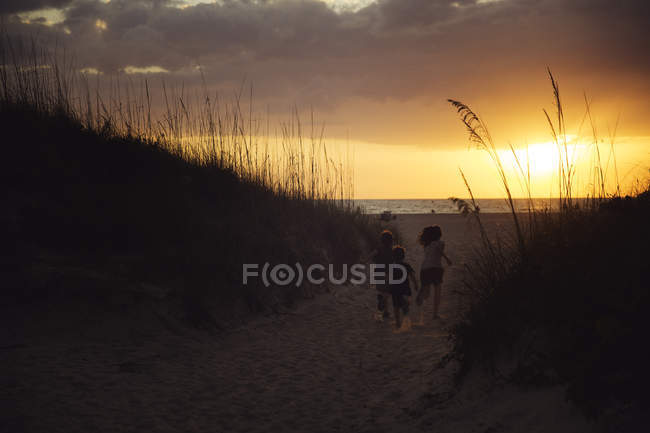 Crianças correndo na praia arenosa — Fotografia de Stock