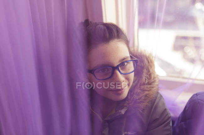 Chica en gafas sentado en el alféizar de la ventana - foto de stock