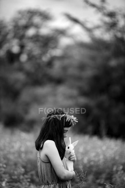 Girl in floral wreath holding rabbit — Stock Photo