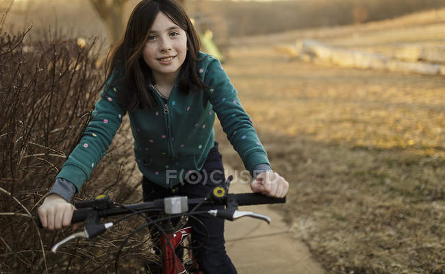 Smiling brunette girl riding bicycle — Stock Photo