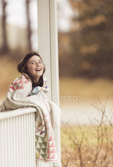 Sonriente chica morena envuelta en manta - foto de stock