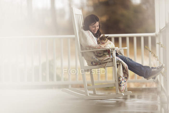 Girl holding cat in rocking chair — Stock Photo