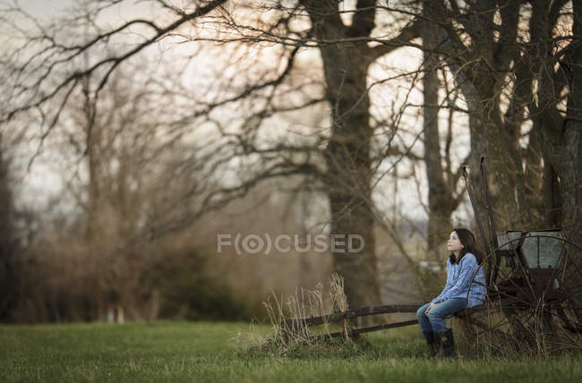 Brunette girl sitting on old wheelbarrow — Stock Photo