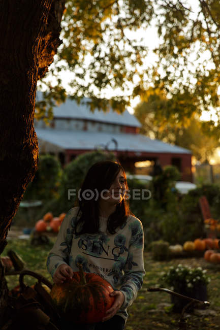 Mädchen hält Kürbis im Herbstgarten — Stockfoto