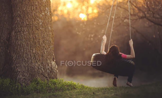 Girl resting on tyre swing — Stock Photo