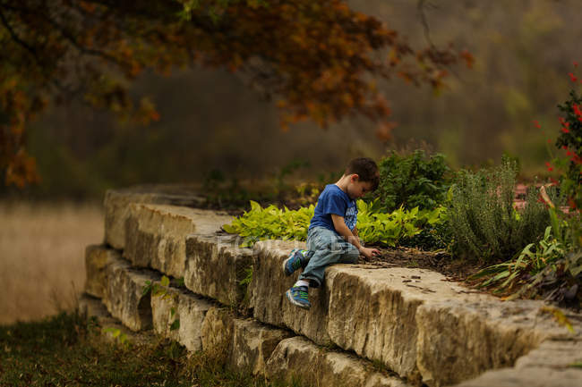 Entzückender kleiner Junge sitzt im Garten — Stockfoto