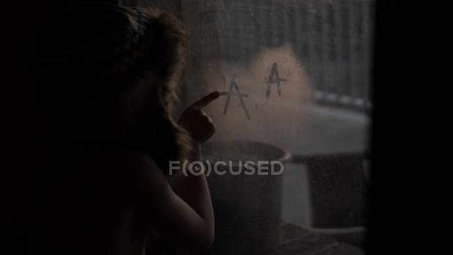 Мальчик рисует через туманное окно — стоковое фото