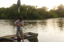 Ragazzo in piedi sul molo con pagaia — Foto stock
