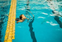Jeune enfant nageant dans la piscine — Photo de stock