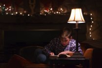 Garçon lecture livre sur table basse — Photo de stock