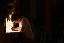 Junge schreibt Brief im dunklen Raum — Stockfoto